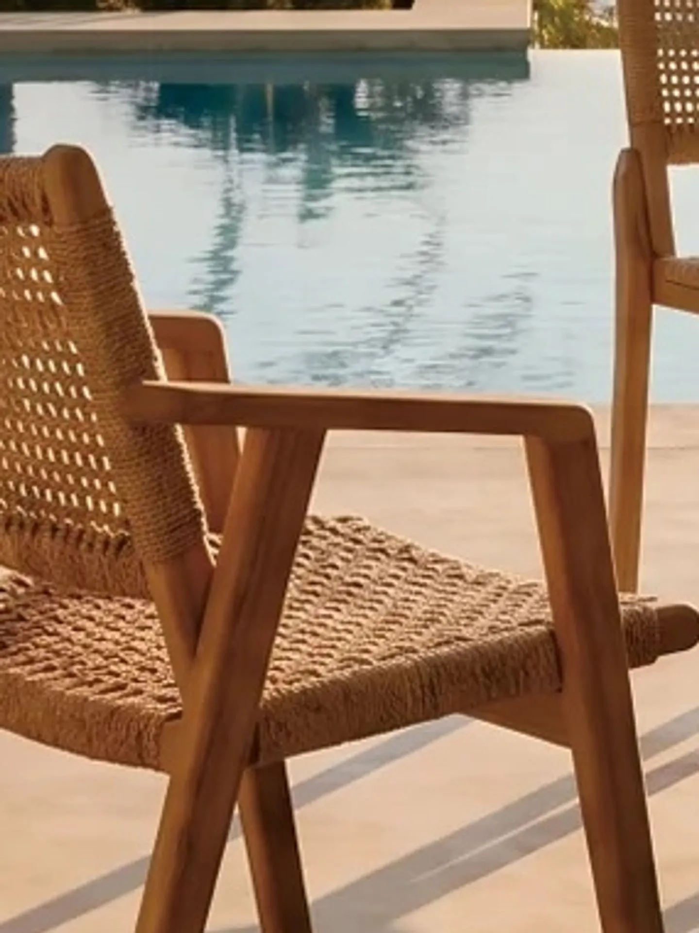Silla de teca con asiento de cuerda trenzada junto a una piscina