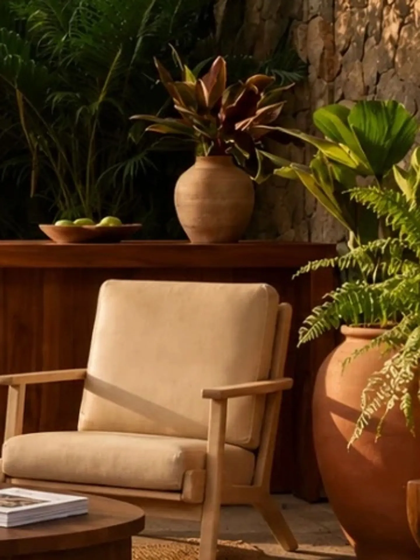 Butaca de teca con cojines de lino en una terraza con plantas